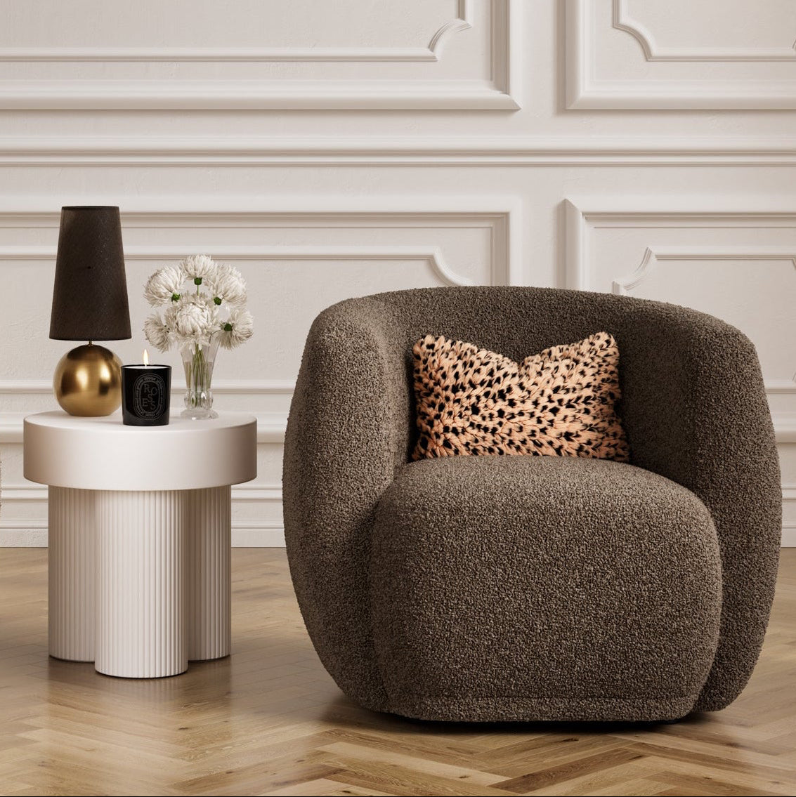 Brown armchair with a small white round side table and decorative items in a room with white panelled walls.