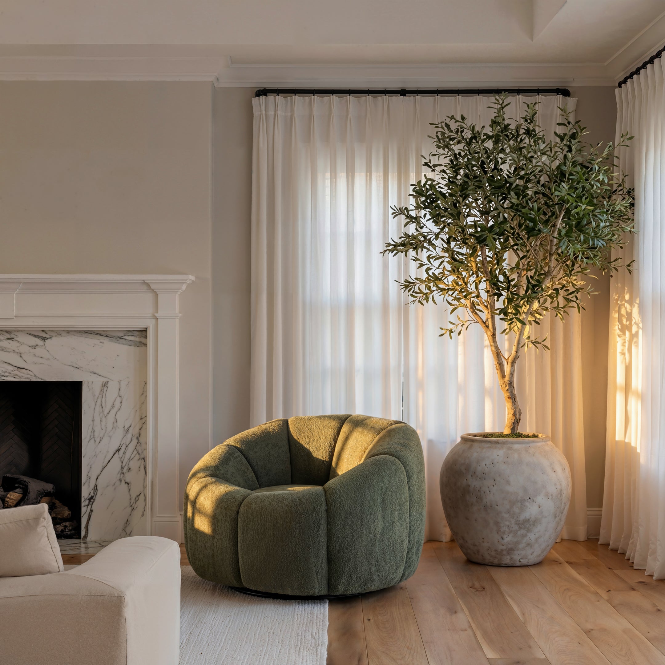 Green round boucle swivel chair and olive tree