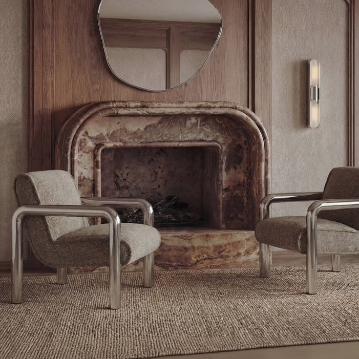 Two chairs in a room with a rustic fireplace and round mirror on a wooden panel.