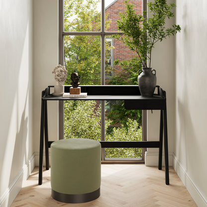 Matte black desk with single drawer next to a sage green stool